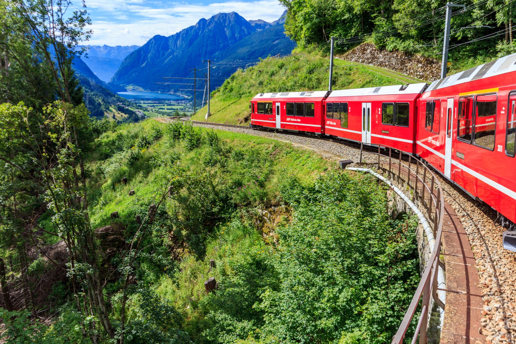 A red alpine train winding through the Swiss mountains